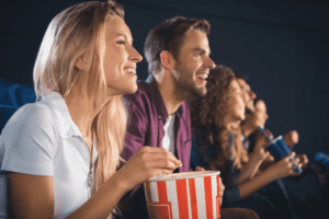 man and woman eating popcorn in movie theater